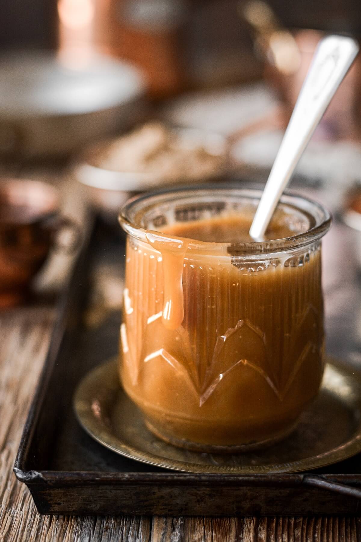 Glass jar of brown sugar toffee sauce with a drip spilling over the edge.