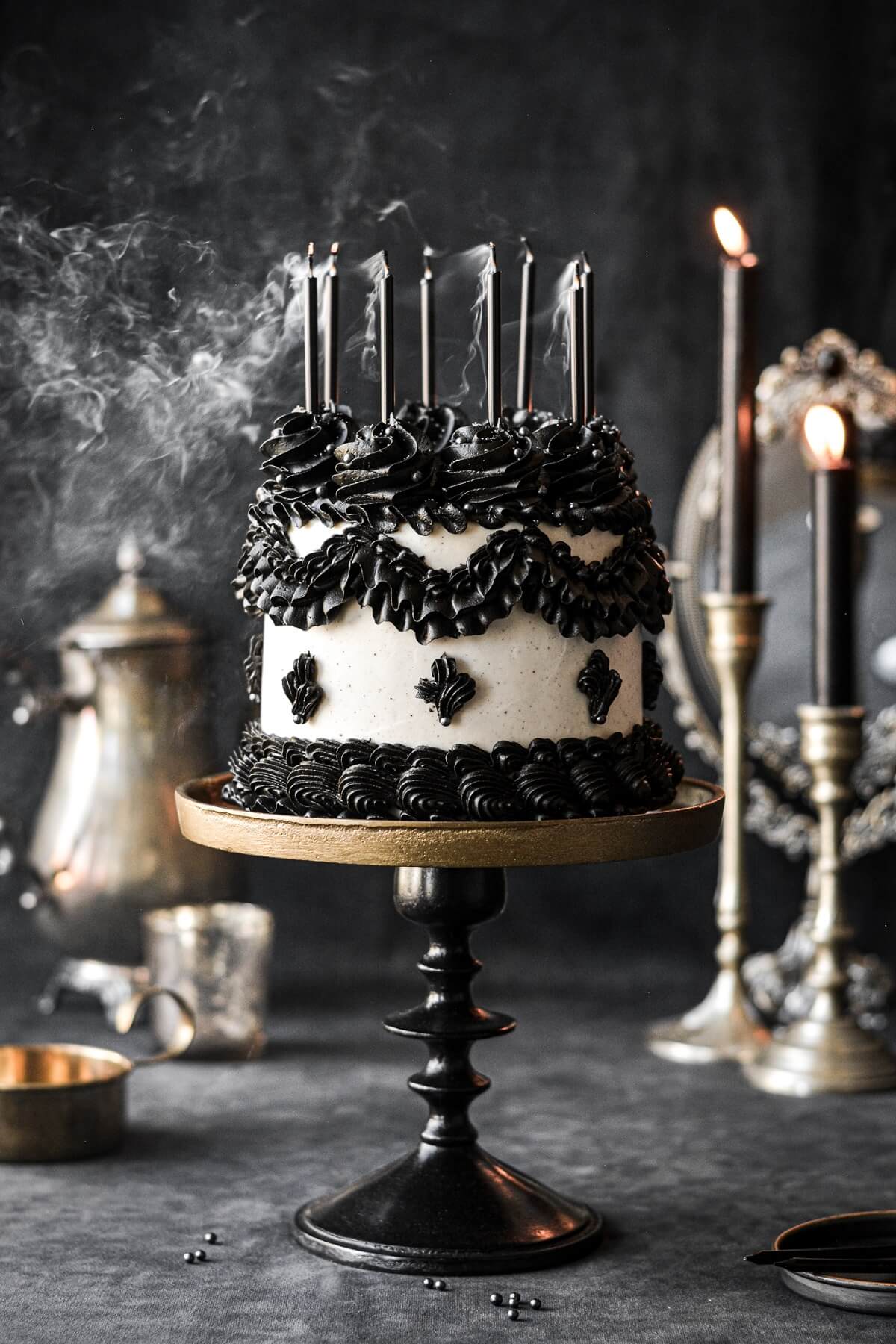 Smoke drifting off candles on top of a black and white Lambeth cake.