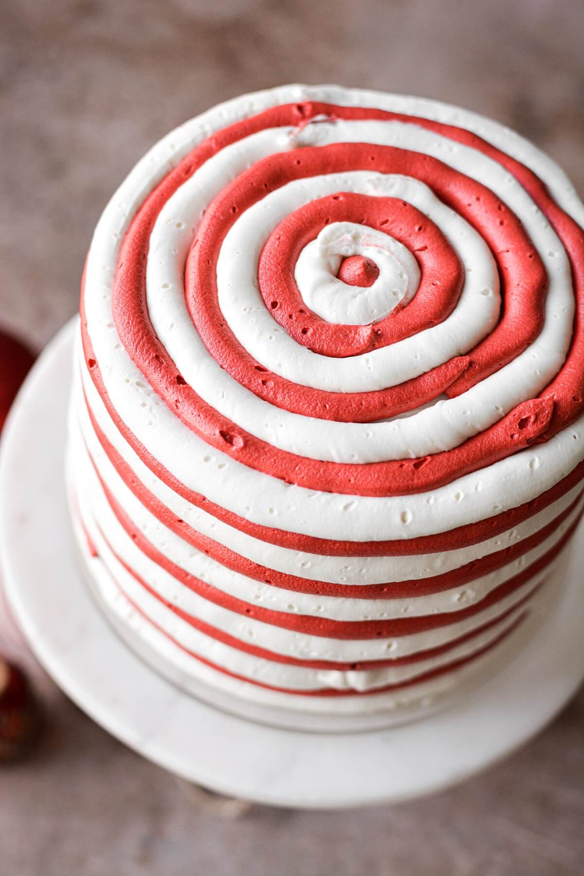 Step 4 for frosting a cake with red and white striped buttercream.