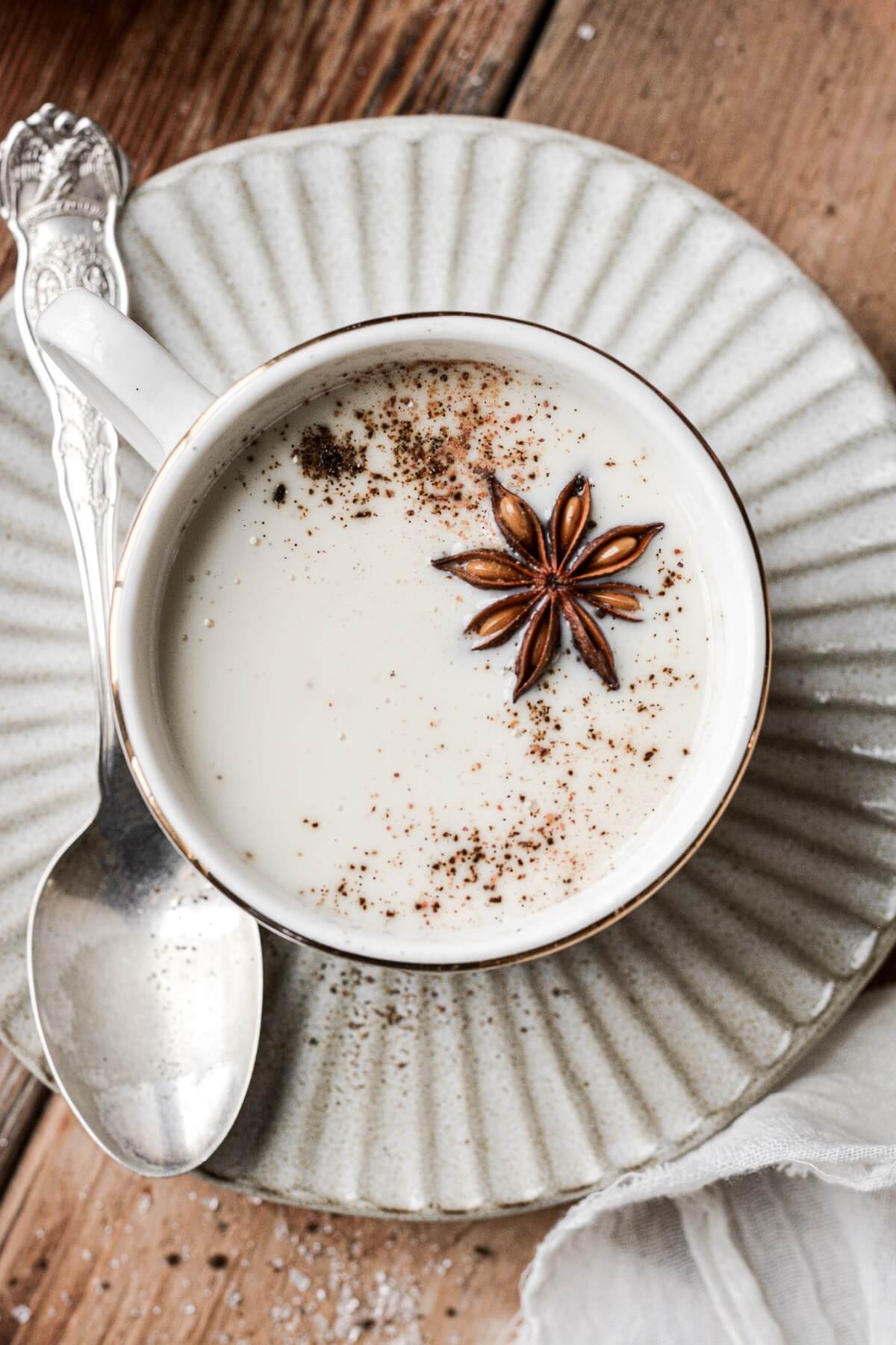 Star anise on top of cup of white hot chocolate.