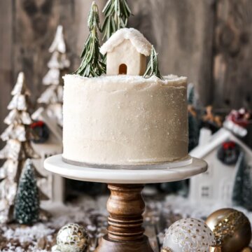 Gingerbread cake topped with rosemary trees and a mini cookie house.