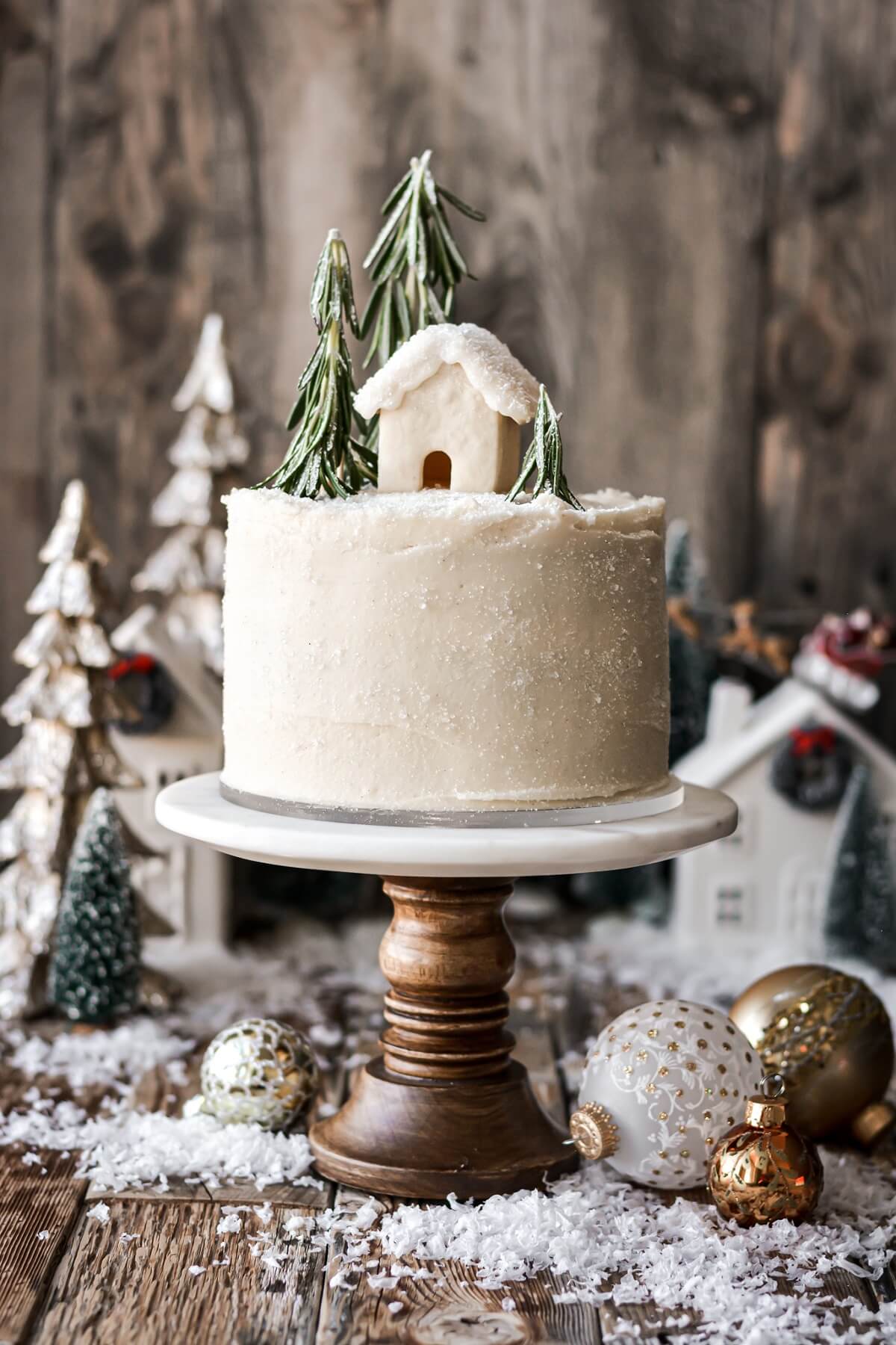 Gingerbread cake topped with rosemary trees and a mini cookie house.