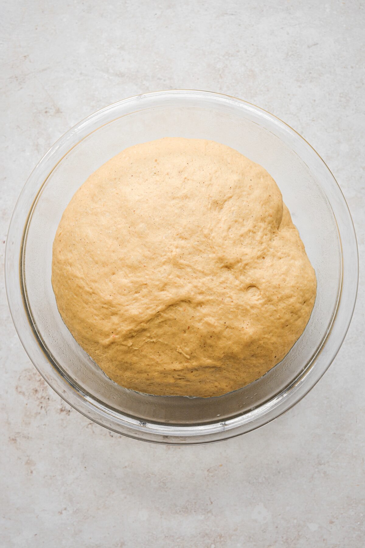 Pumpkin roll dough, risen to the top of a bowl.