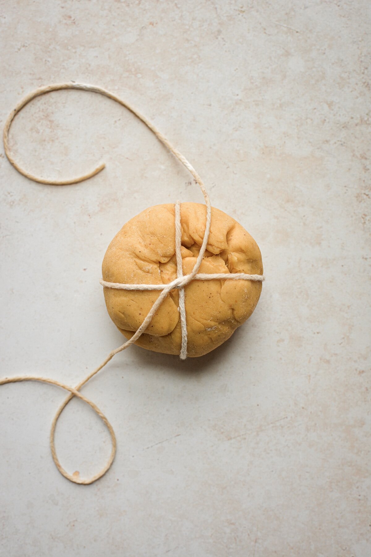 Step 3 for tying pumpkin shaped dinner rolls with twine.