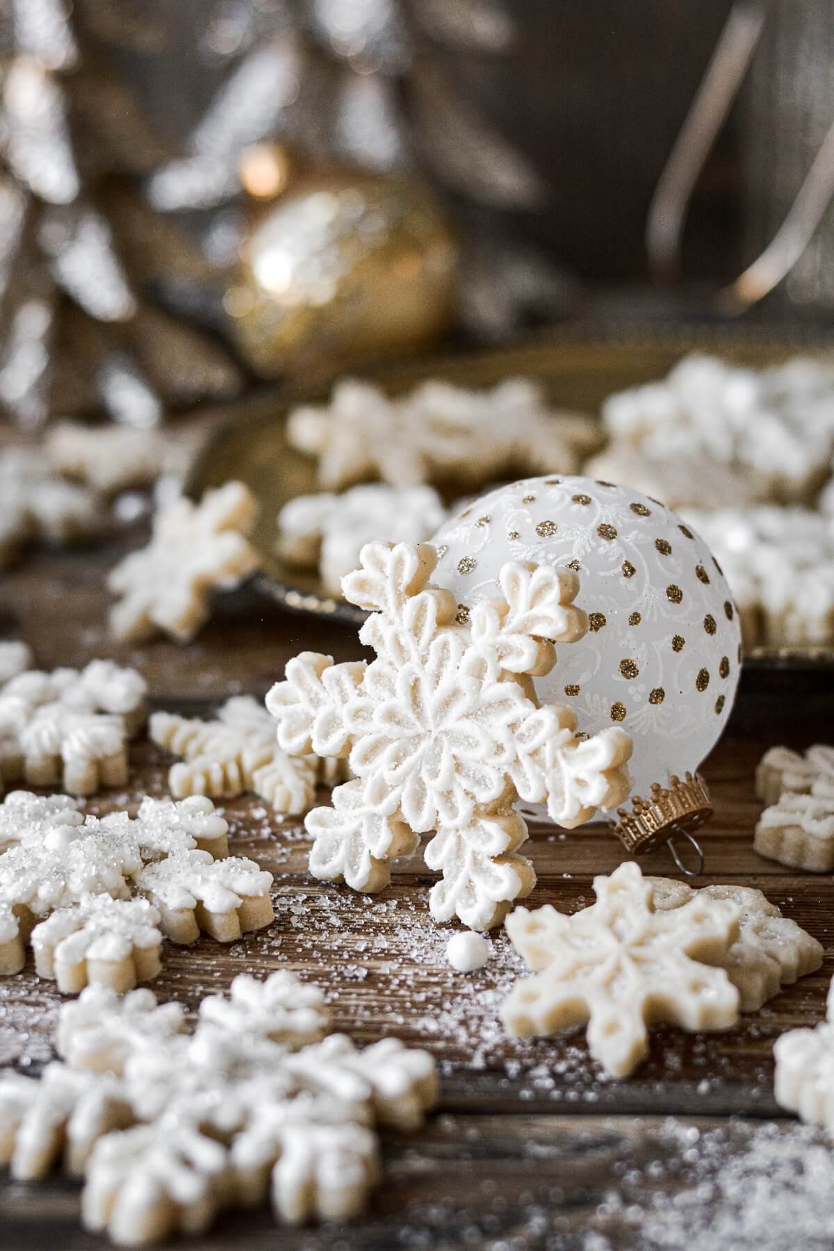 Snowflake sugar cookie resting against a Christmas ornament.