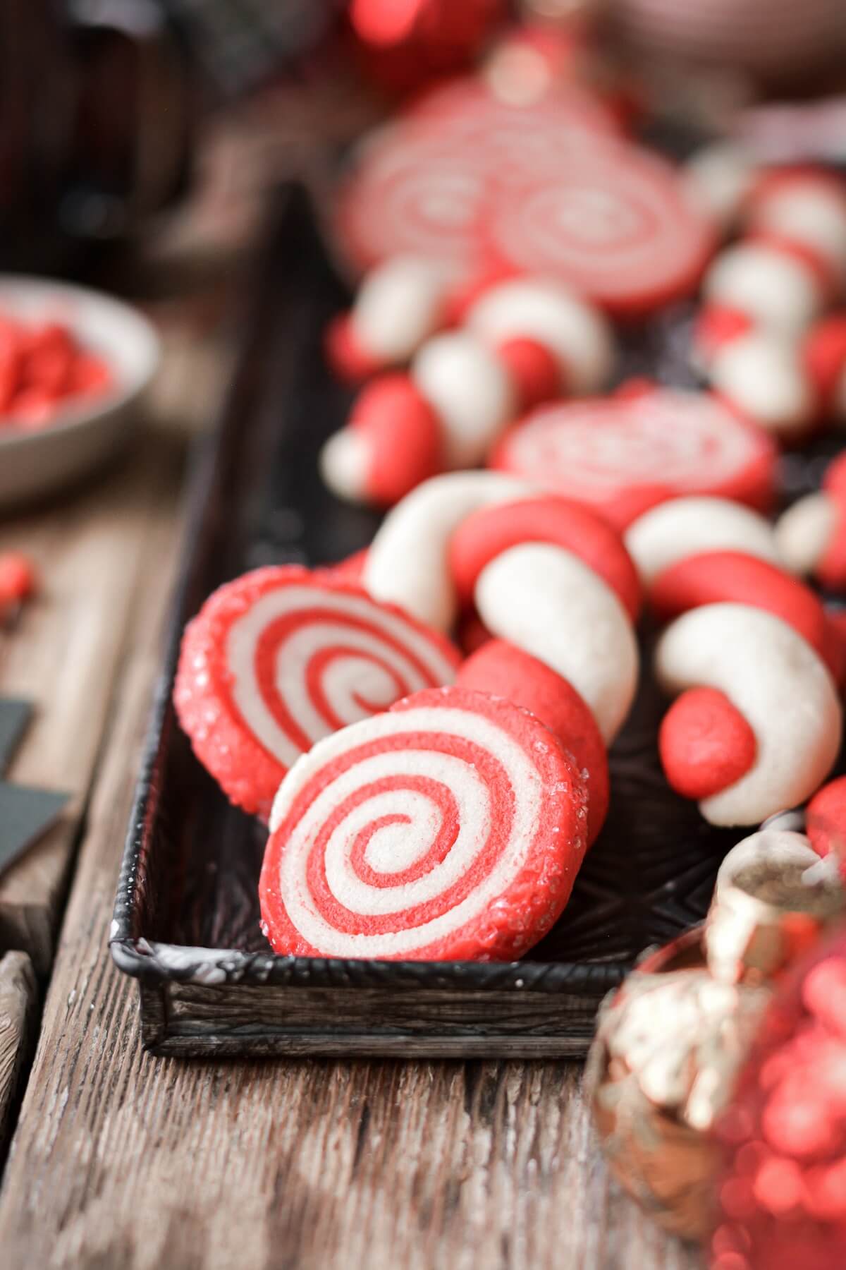 Red and white candy cane cookies and pinwheel cookies on a baking sheet.