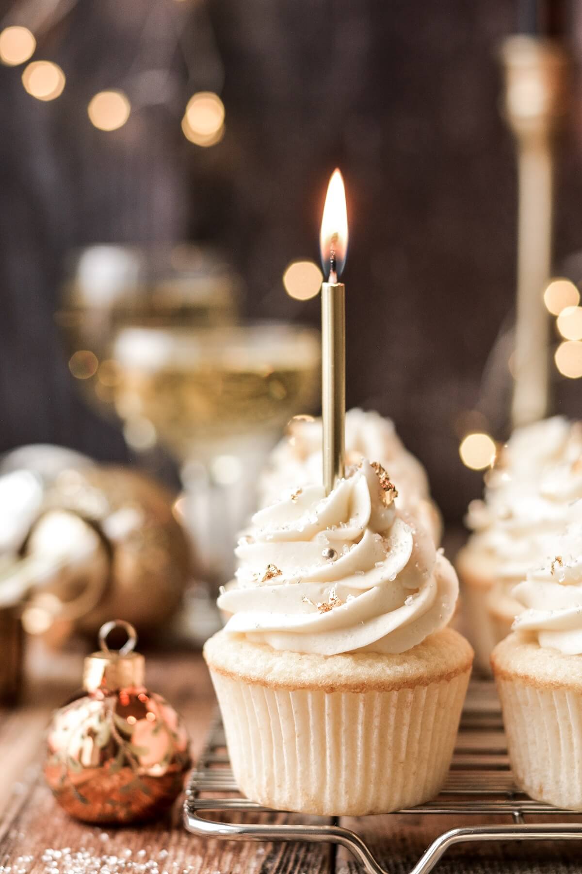 Champagne cupcakes with gold candles and gold sugar pearls.