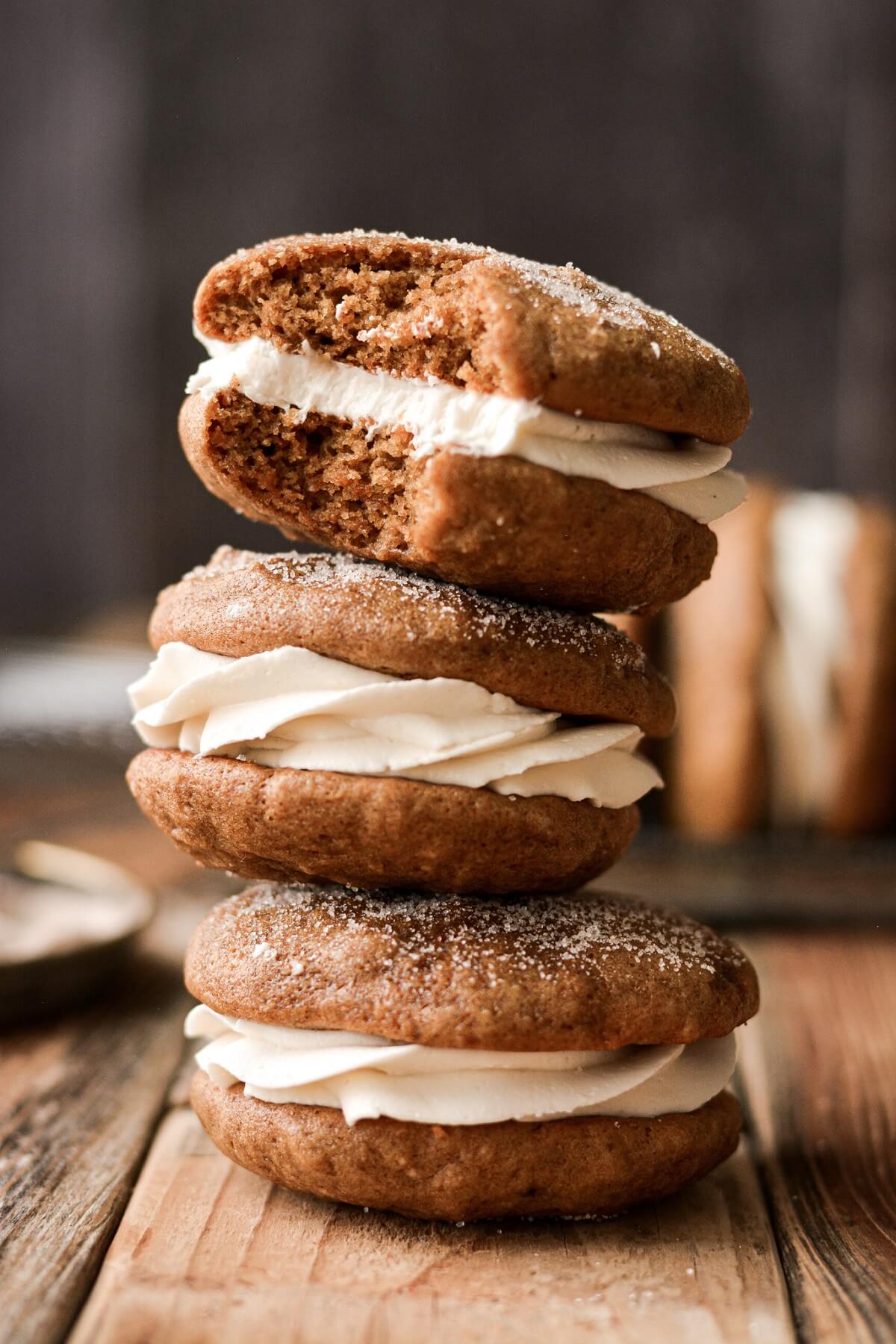 Stack of gingerbread whoopie pies, one with a bite taken.