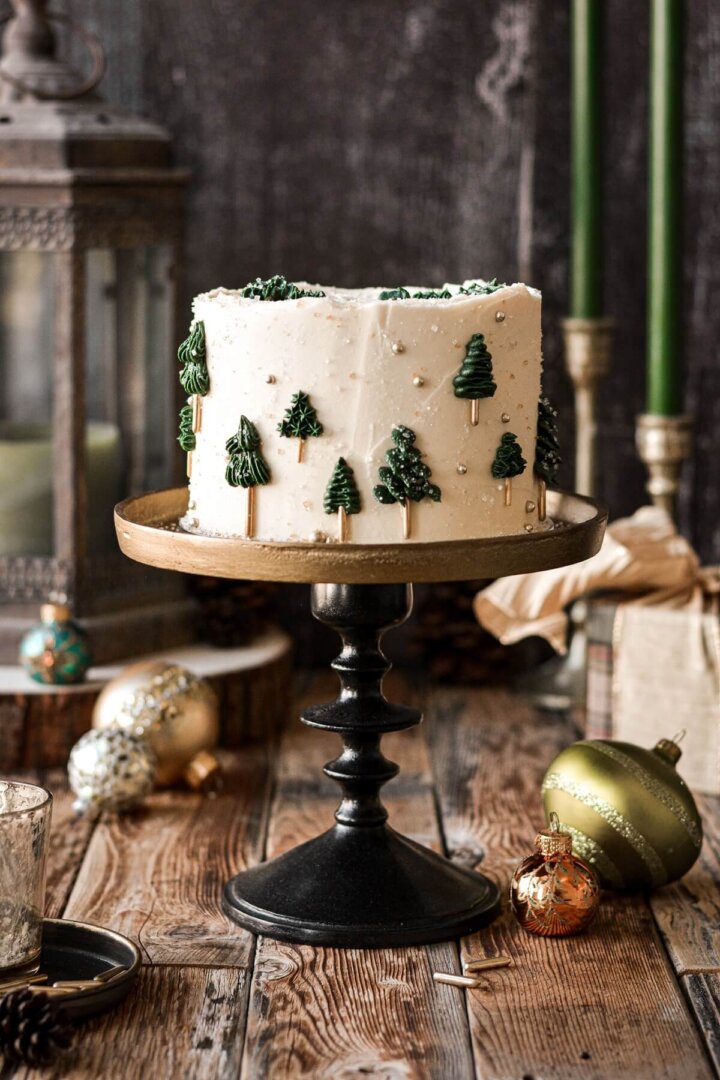 Green and gold Christmas tree cake on a gold and black cake stand.
