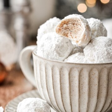 Snowball cookies stacked in a coffee cup.
