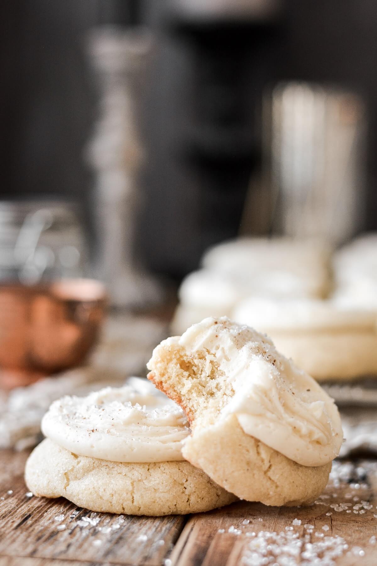 Eggnog cookies with eggnog frosting, one with a bite taken.