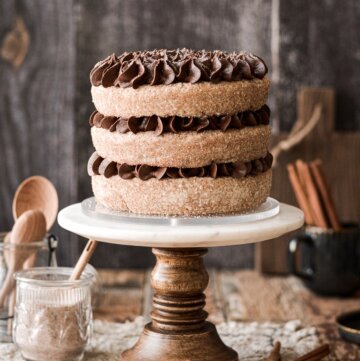 Chocolate cinnamon cake on a marble and wood cake stand.