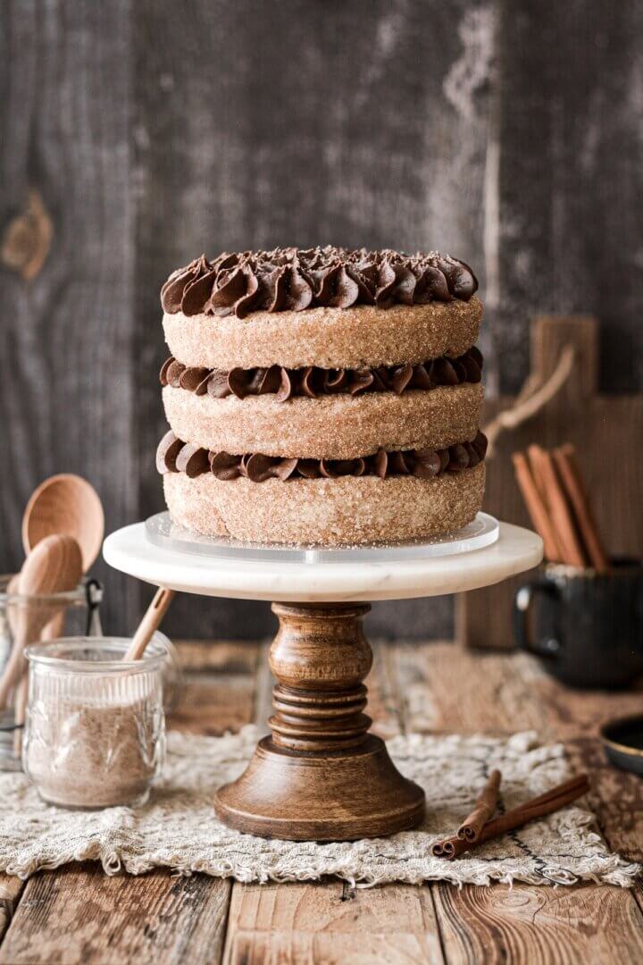 Chocolate cinnamon cake on a marble and wood cake stand.