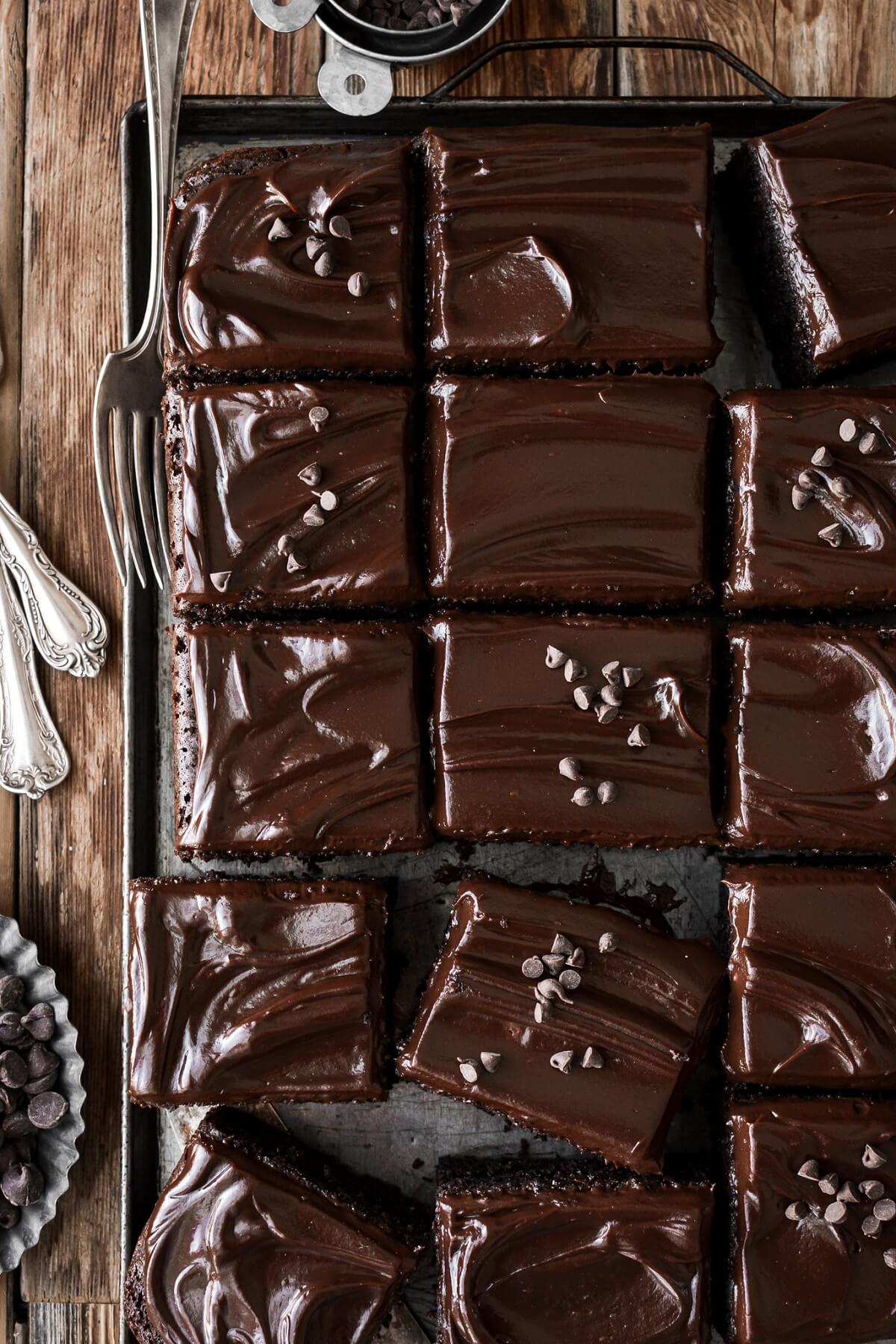 Chocolate sheet cake cut into squares on a baking pan.