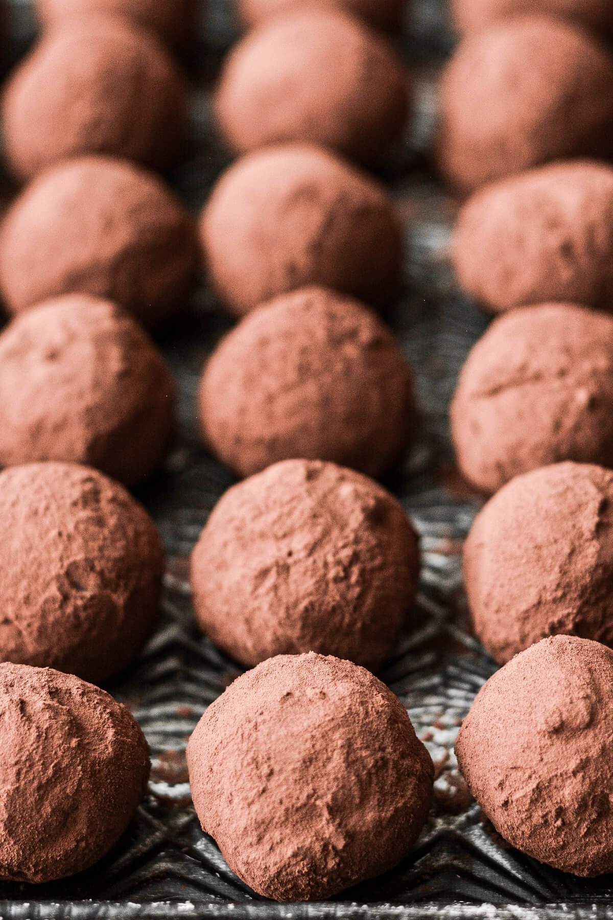 Chocolate truffles covered in cocoa powder on a baking sheet.