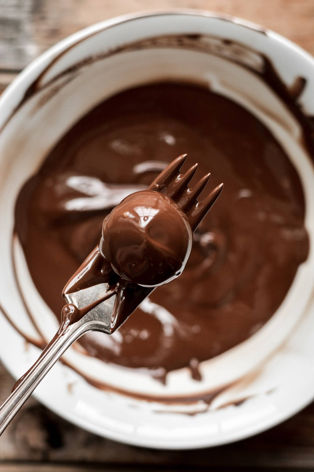 Chocolate truffle being dipped in melted chocolate.