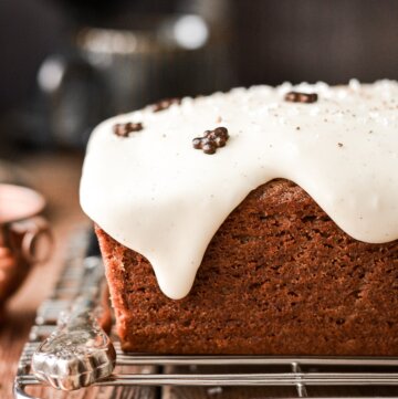 Gingerbread loaf cake with eggnog icing dripping over the edge.