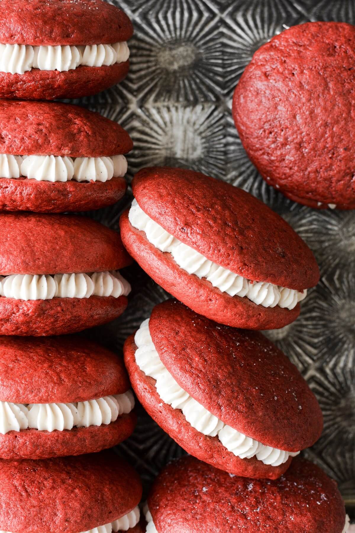 Red velvet cake whoopie pies filled with cream cheese frosting.