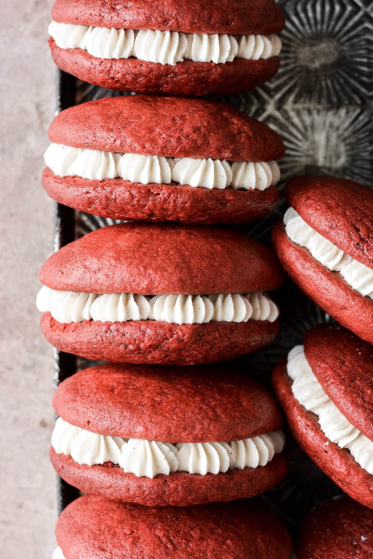 Red velvet cake whoopie pies filled with cream cheese frosting.