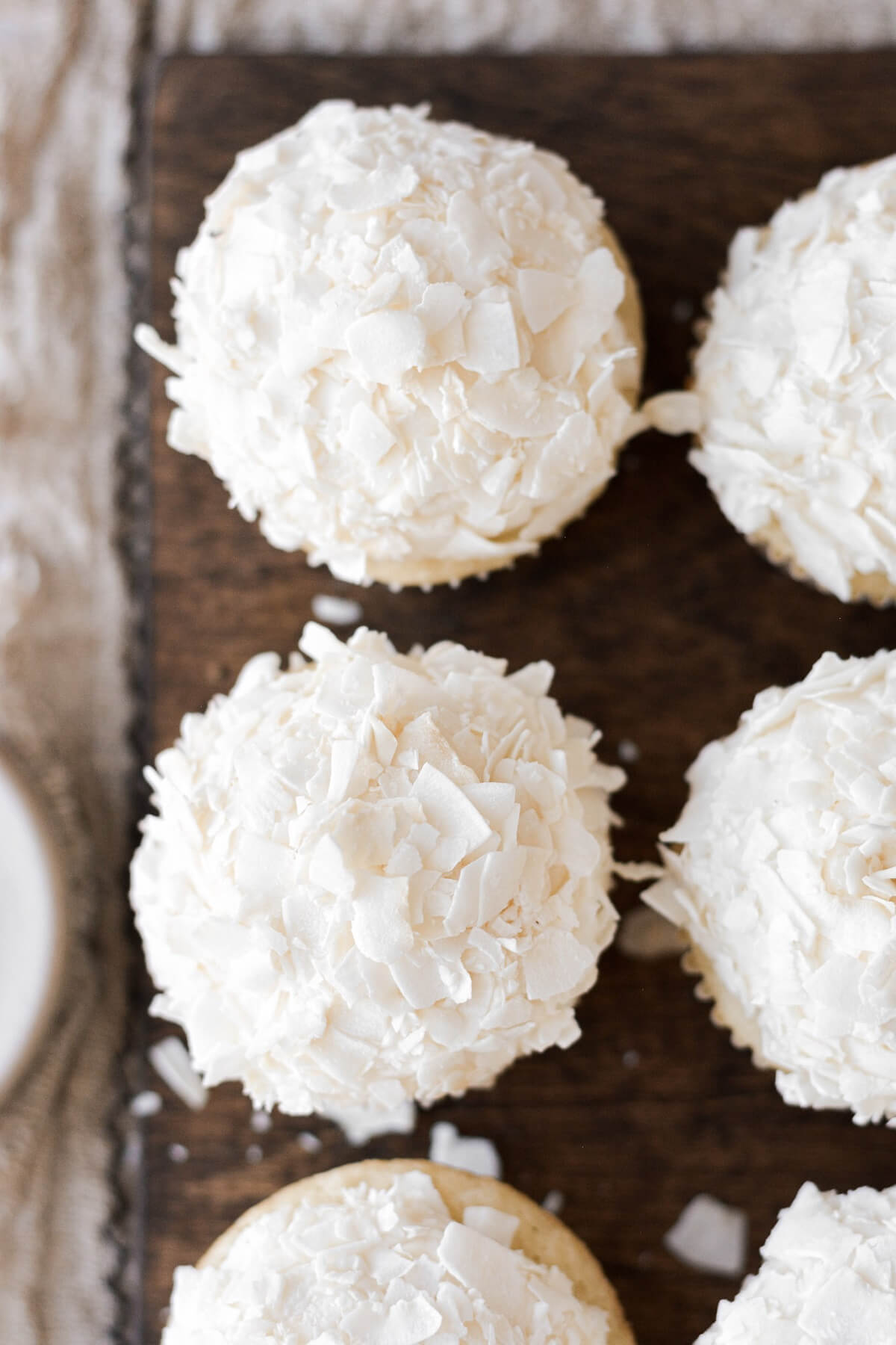 Coconut cupcakes covered in coconut flakes.