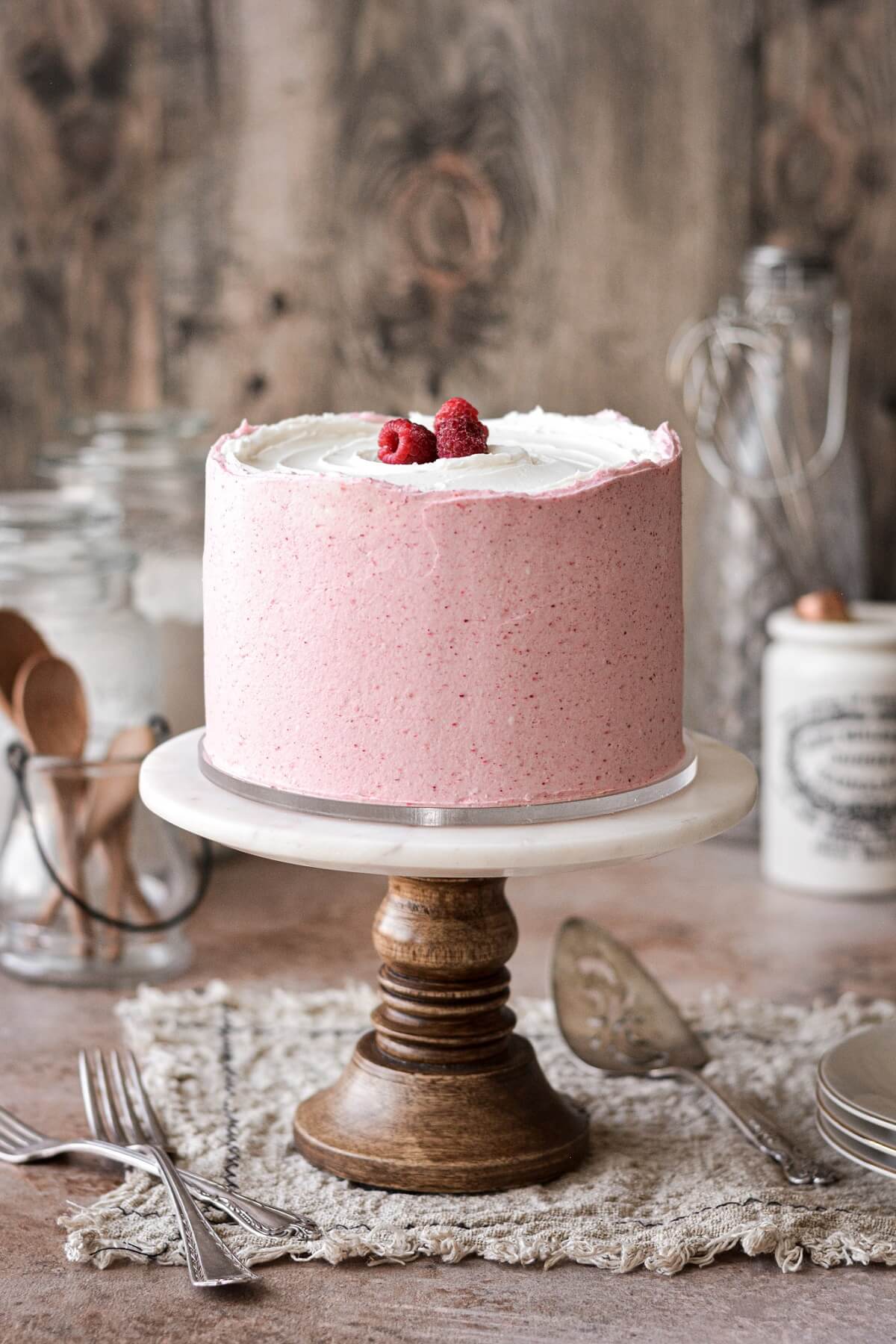 Raspberry vanilla cake with pink raspberry buttercream topped with raspberries.