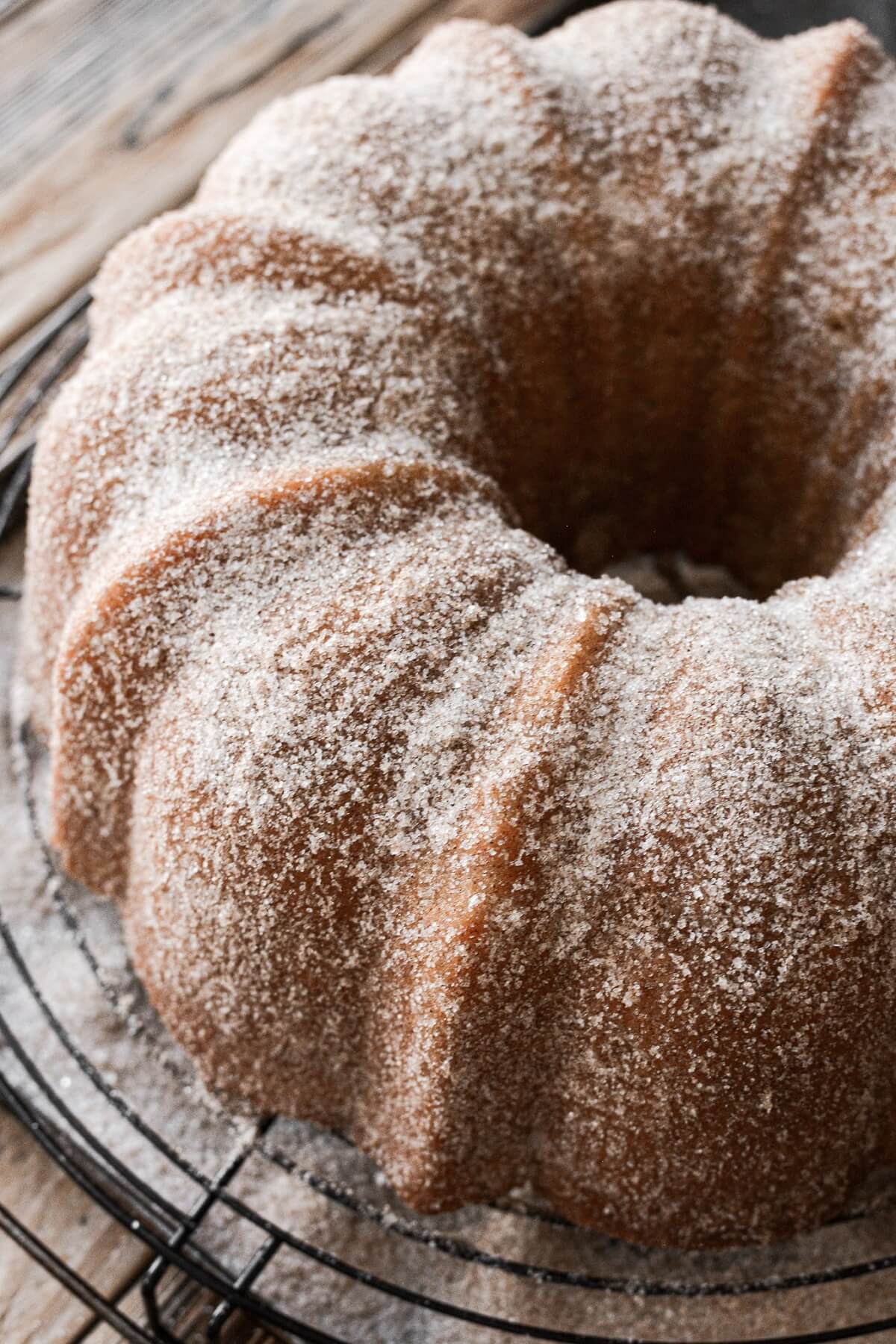 Snickerdoodle bundt cake with cinnamon sugar on a cooling rack.