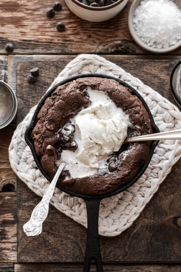 Mini double chocolate skillet cookie with ice cream and two spoons.