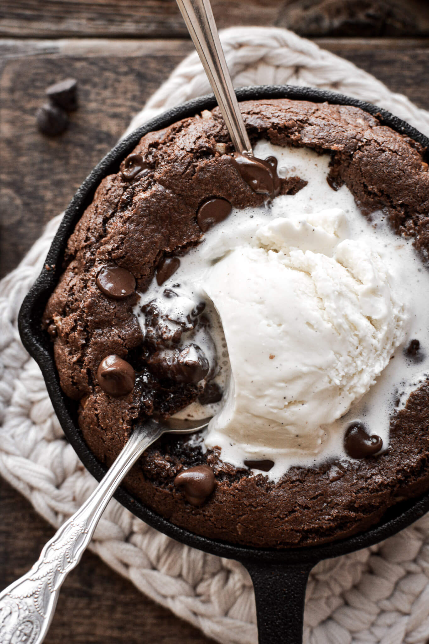 Mini double chocolate skillet cookie with vanilla ice cream and two spoons.