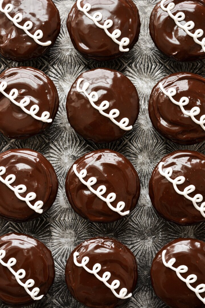 Homemade chocolate hostess cupcakes with ganache and curly white icing.