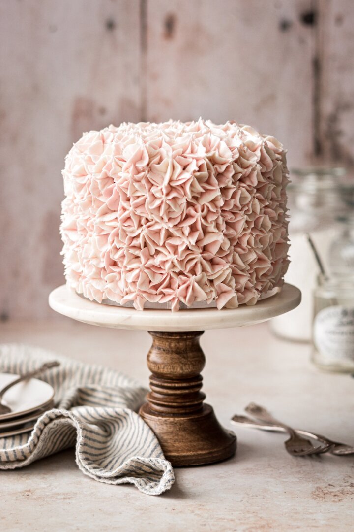 Pink hydrangea cake on a wood and marble cake stand.