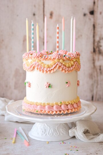 Birthday cake with pastel piped buttercream and candles.