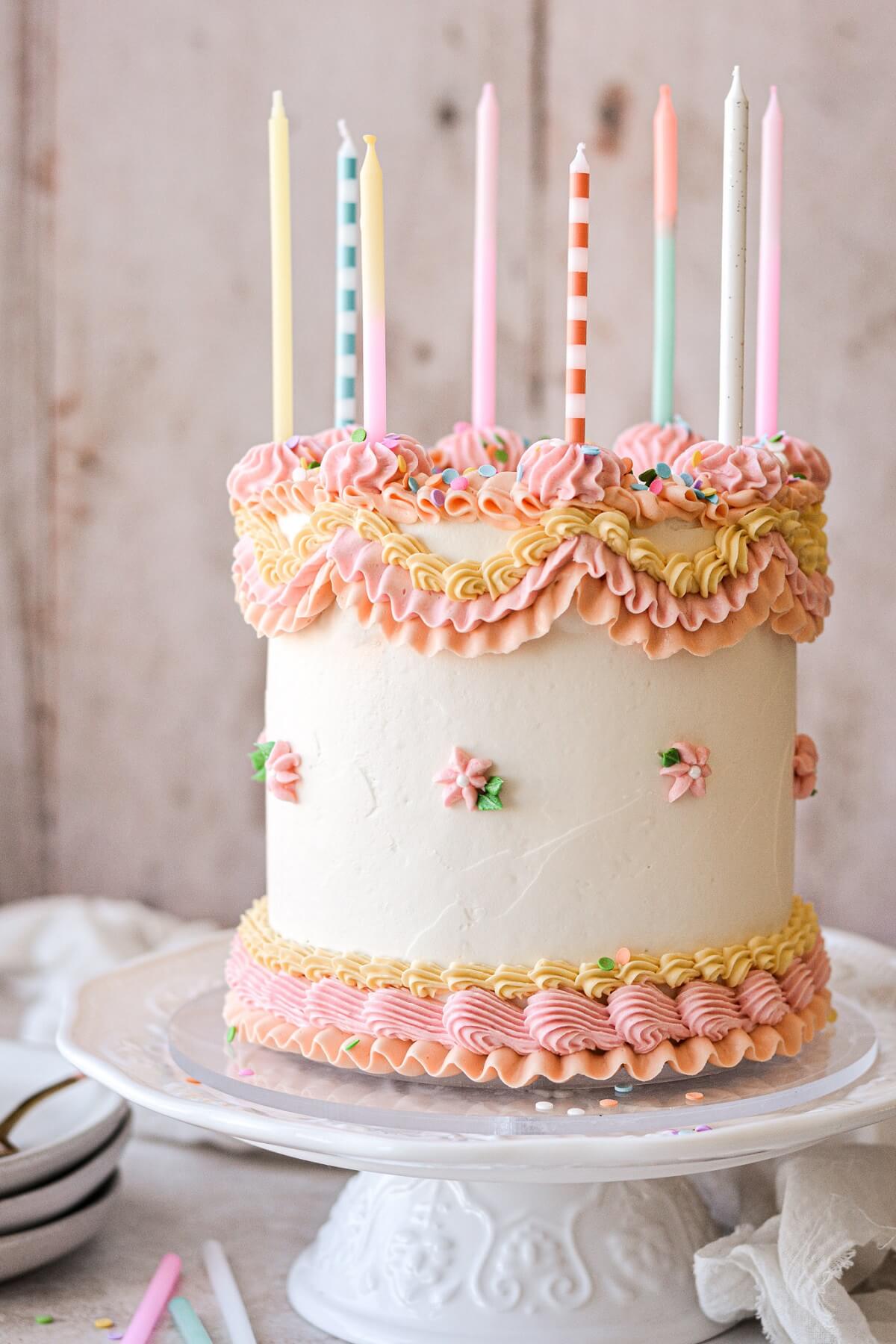 Birthday cake with pastel piped buttercream and candles.