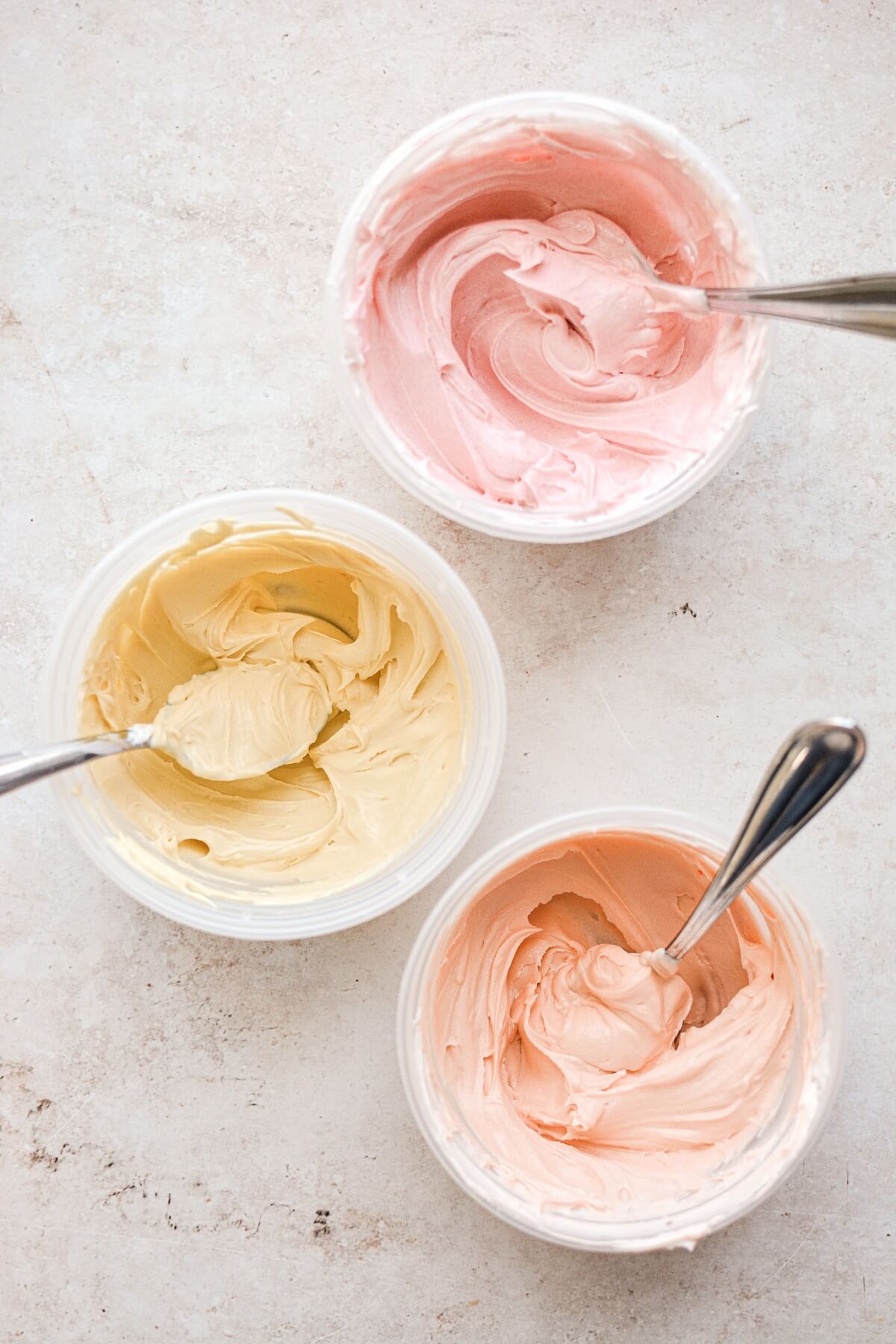 Bowls of pink, yellow and orange buttercream.