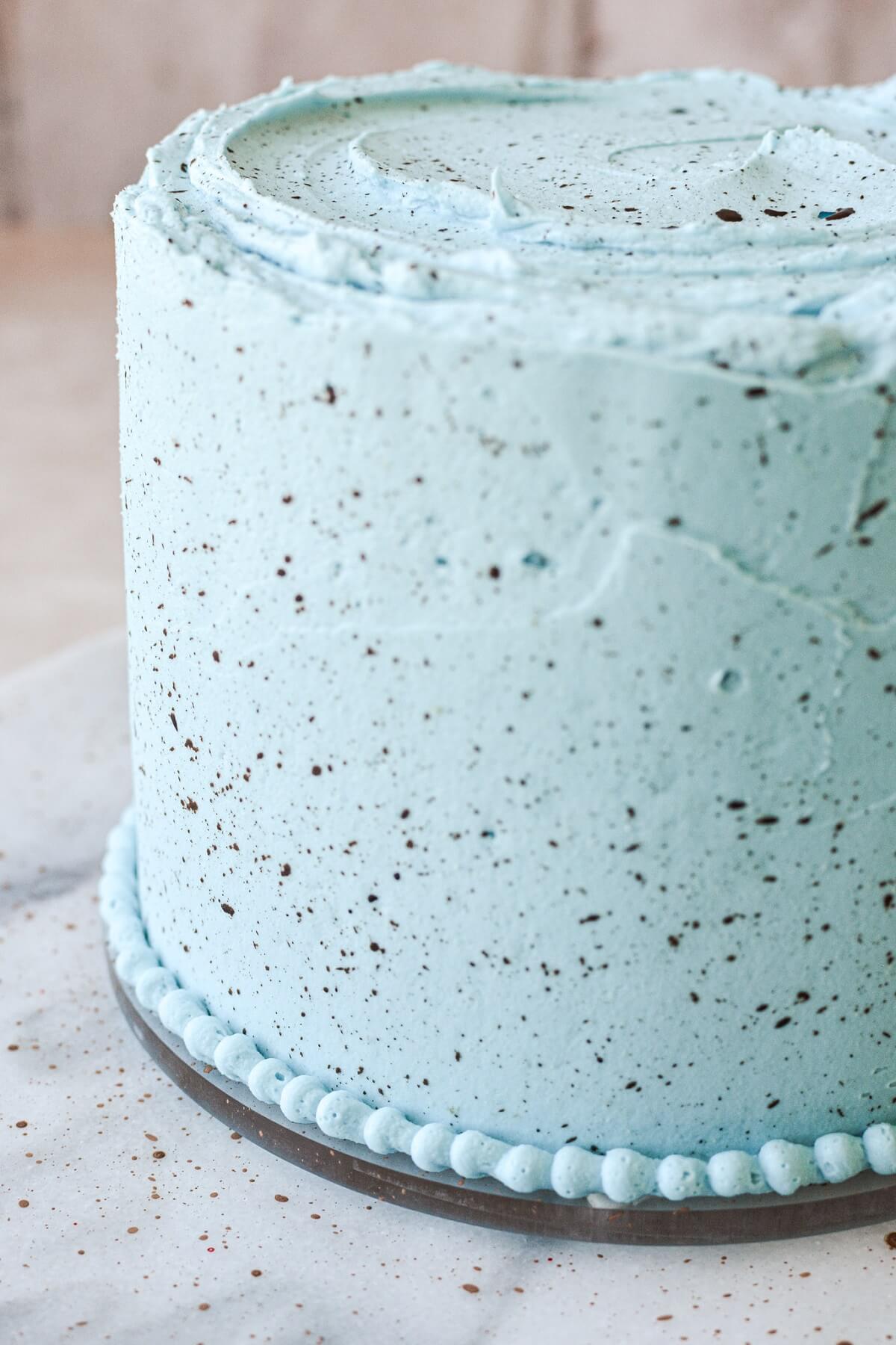 Blue frosted cake spattered with brown specks to look like an eggshell.