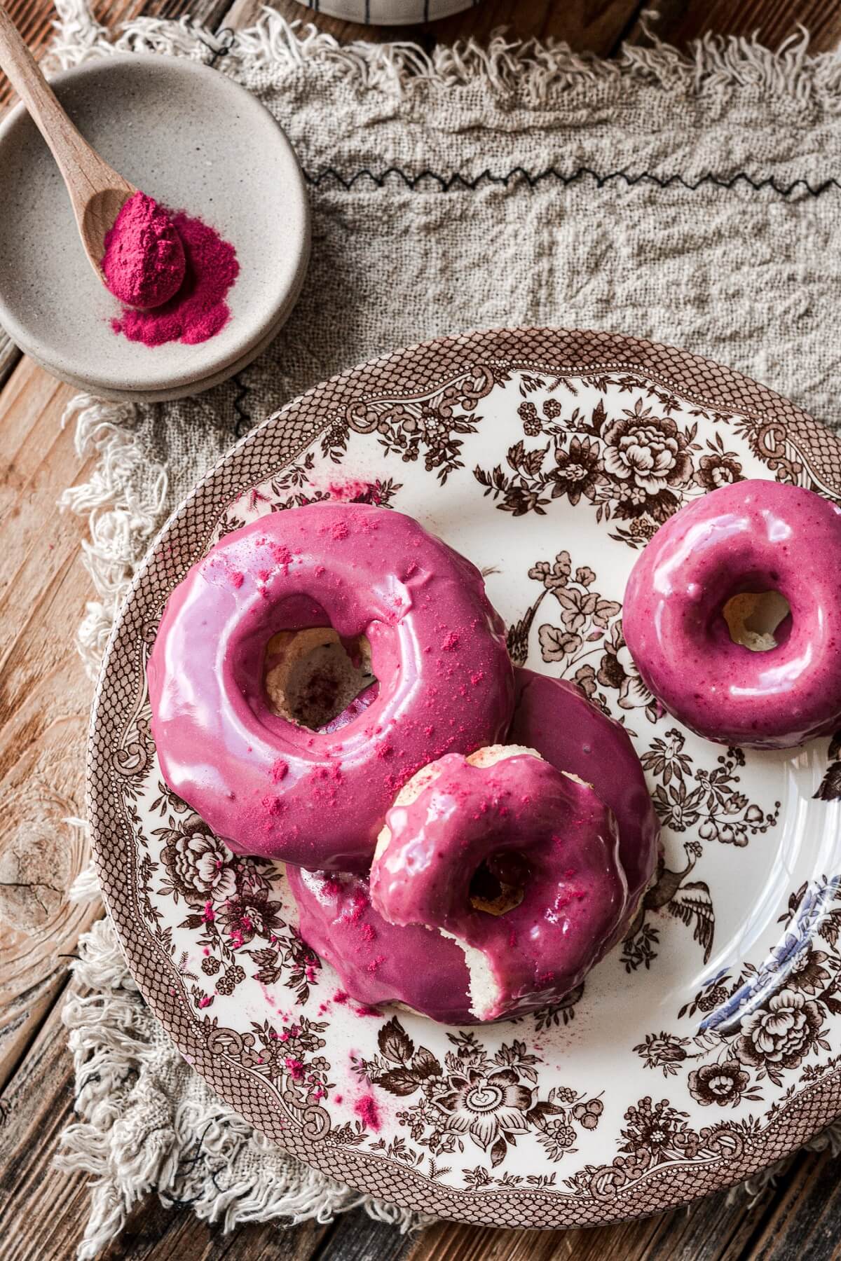 Baked blueberry donuts on a brown and white floral plate.