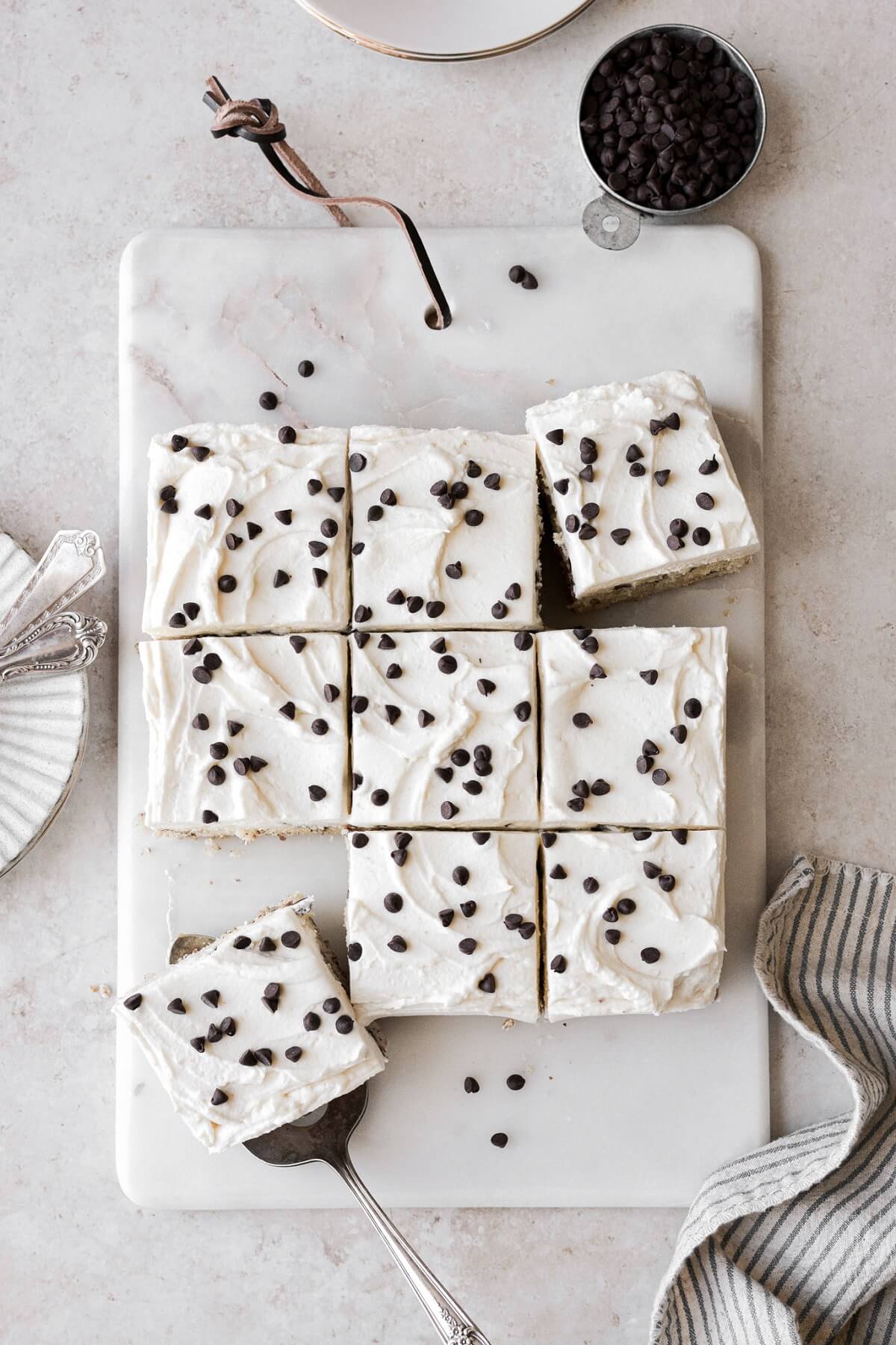 Squares of chocolate chip cake on a marble board.