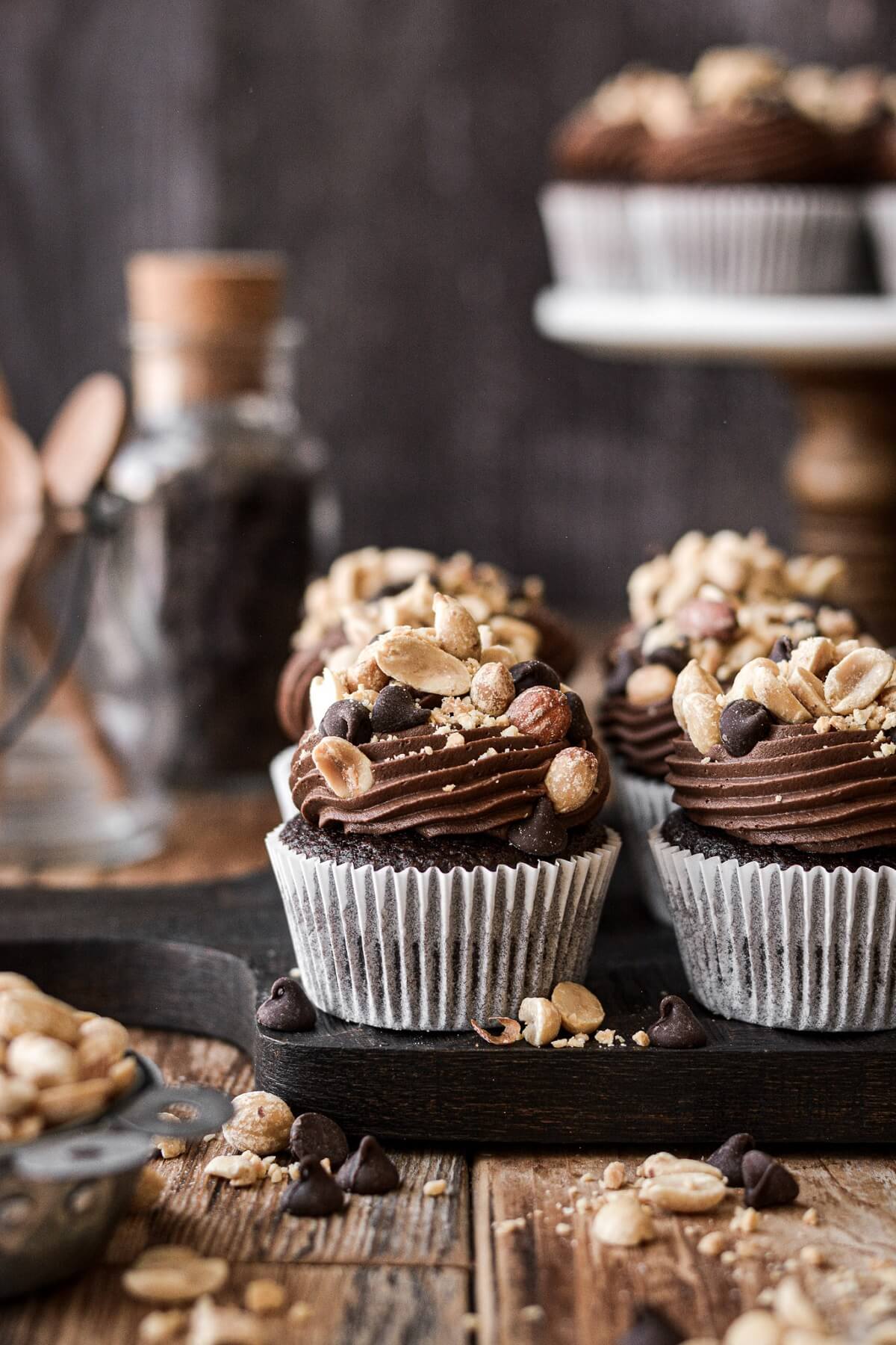Chocolate peanut cluster cupcakes, with salted peanuts and chocolate chips on top.