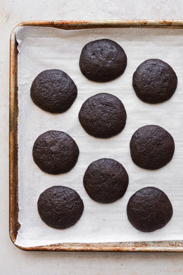 Chocolate whoopie pies on a baking sheet.