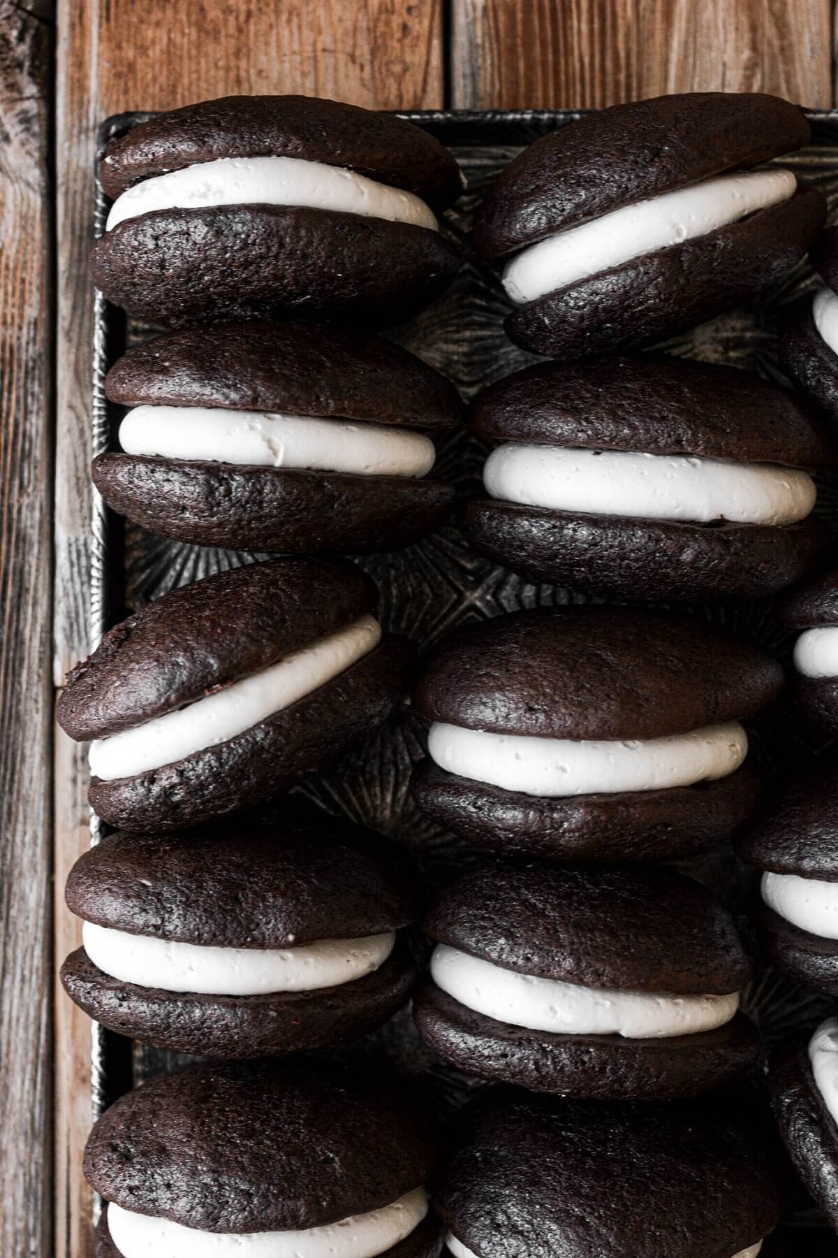 Chocolate whoopie pies with cream filling on a baking sheet.
