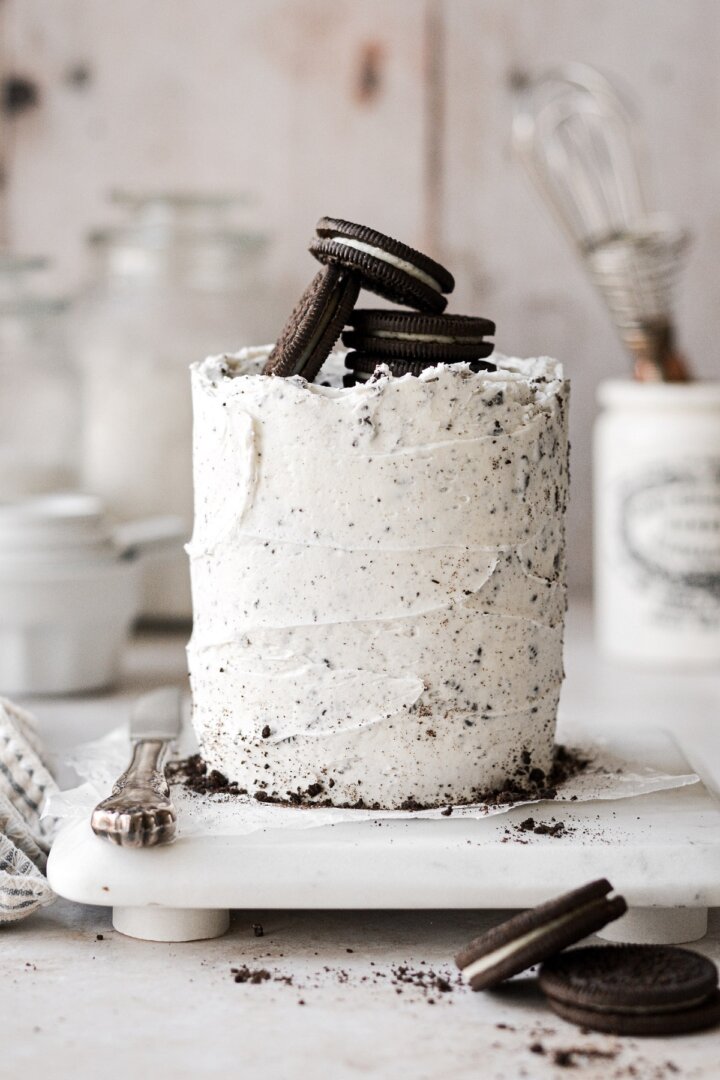 Mini cookies and cream cake topped with Oreos, on a white marble board.