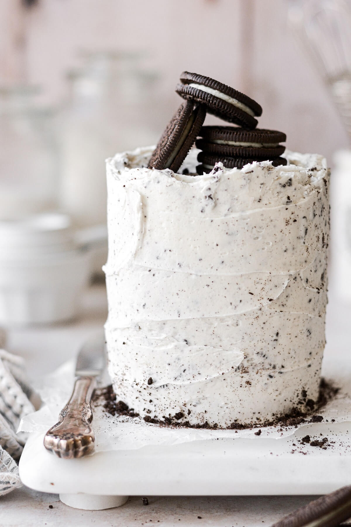 Mini cookies and cream cake topped with Oreos, on a white marble board.