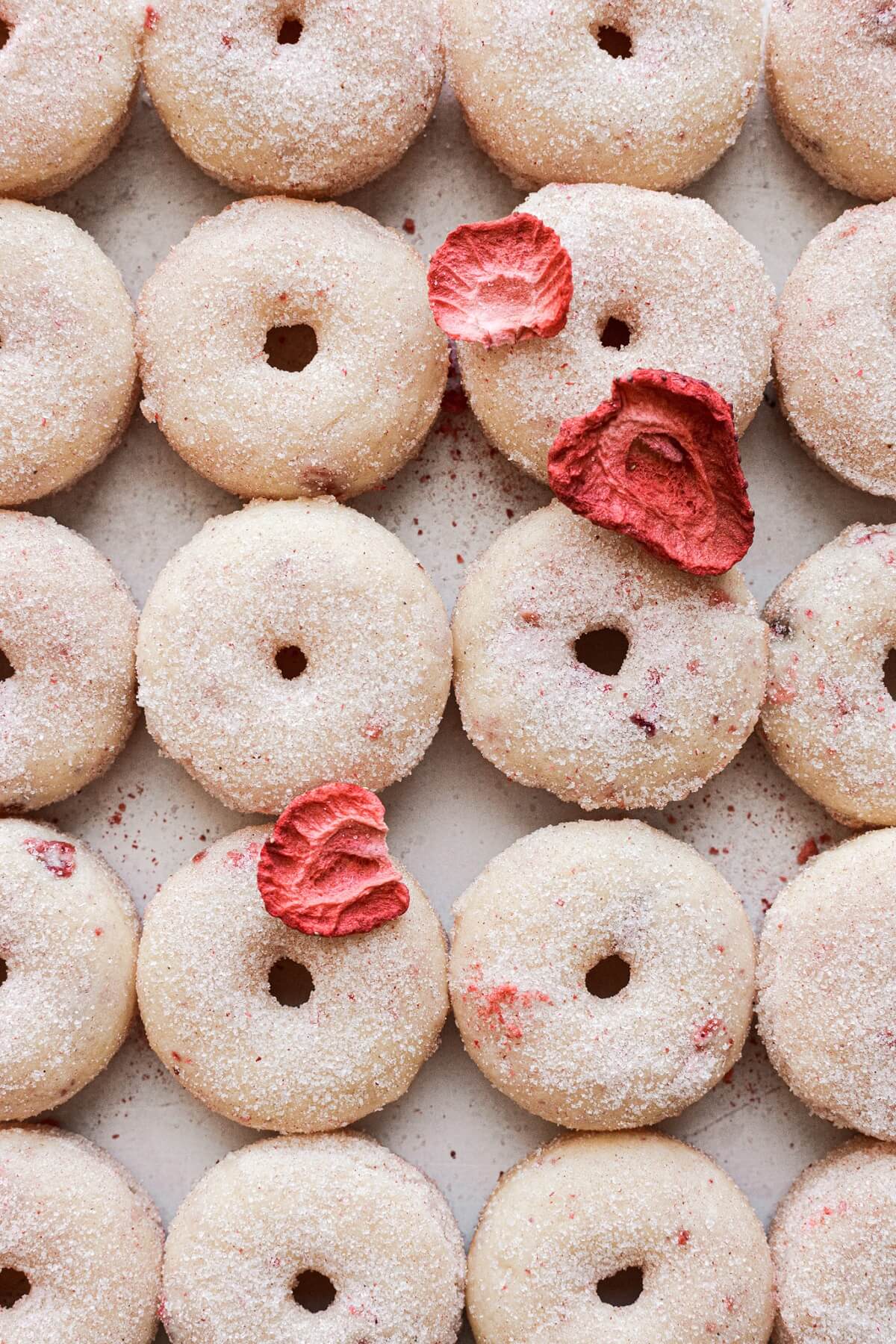Baked mini strawberry donuts coated in strawberry sugar.