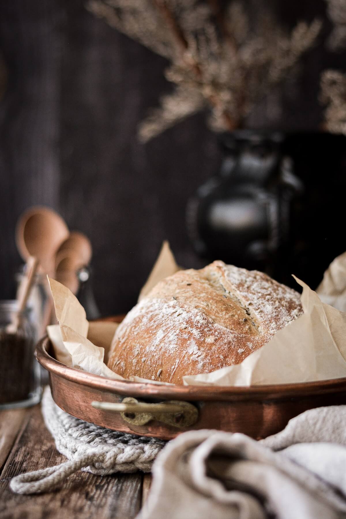 A rustic loaf of no knead bread in a copper pan.