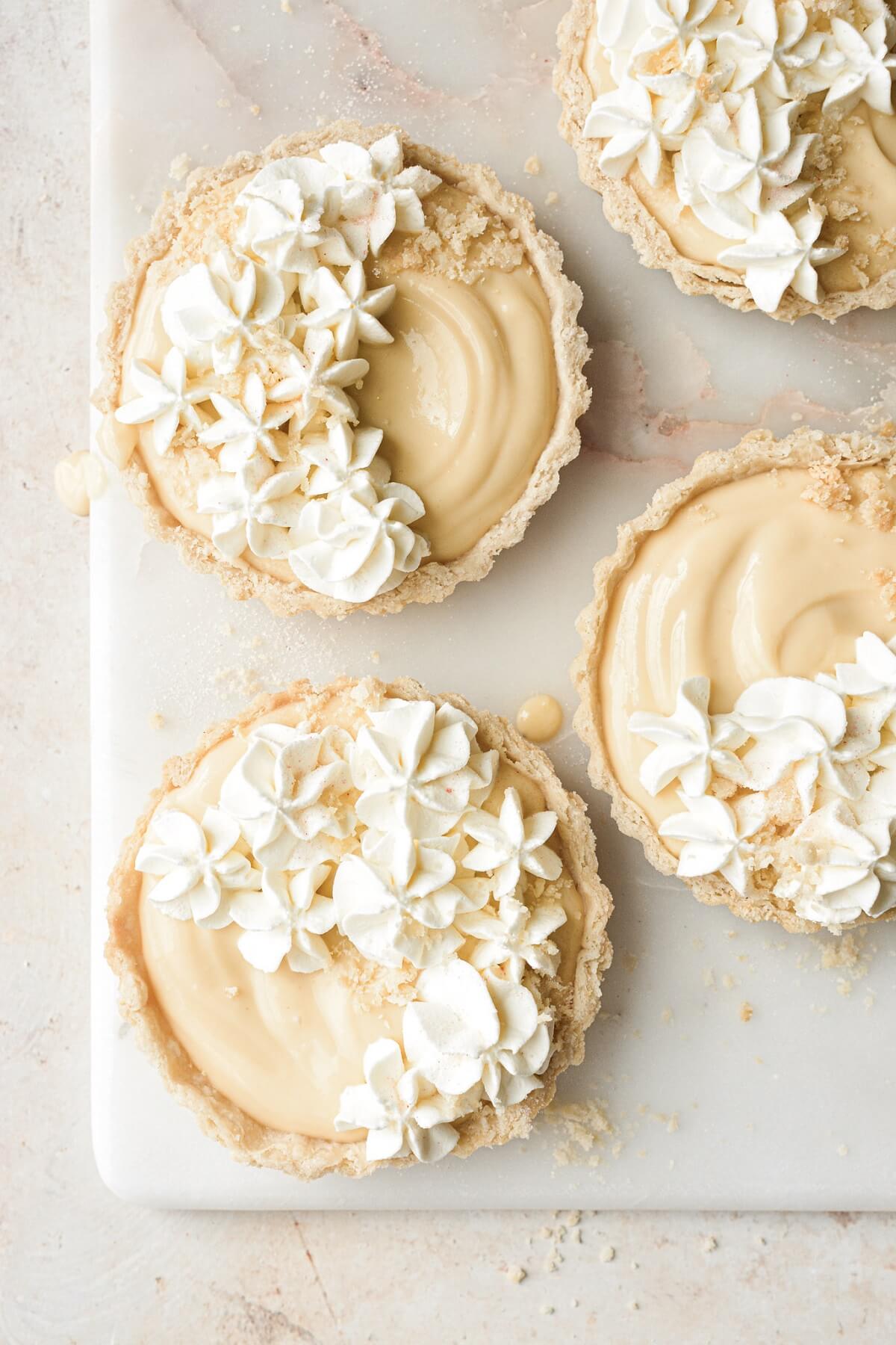 Whipped cream cheese piped on top of grapefruit tarts.