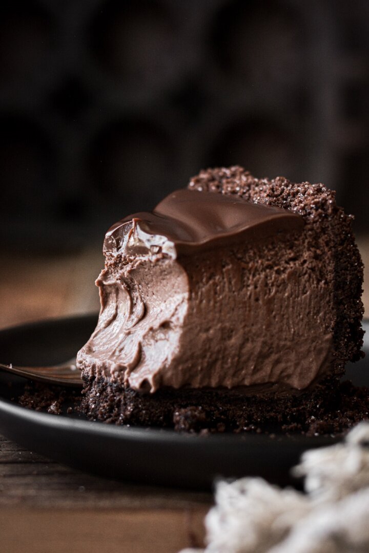A slice of chocolate cheesecake with a bite taken.