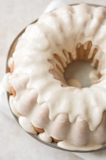 Vanilla icing dripping down a sour cream donut cake.