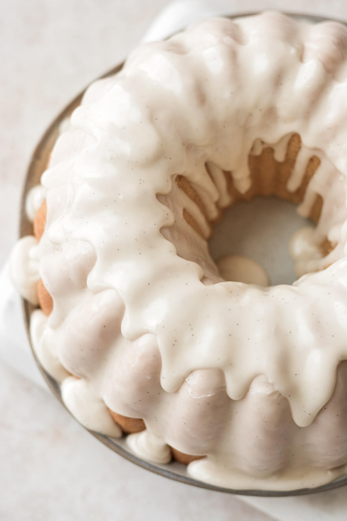 Vanilla icing dripping down a sour cream donut cake.