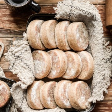 A metal tin of homemade English muffins on a napkin.