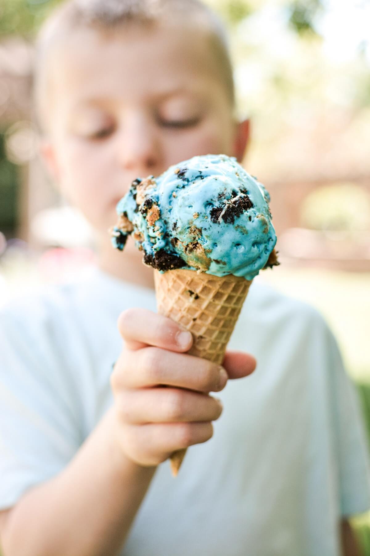 Cookie monster ice cream cone, held by a young boy.