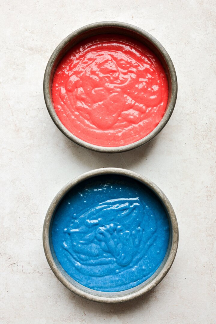 Red and blue cake batter in cake pans.